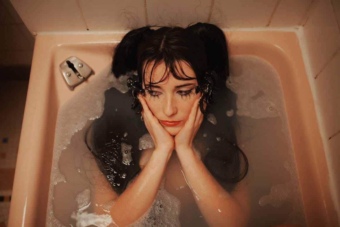 L'image est un portrait de l'artiste Maicee dans une baignoire.La photographie est prise de haut. 